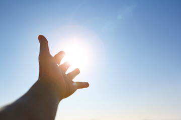 New Year's sunrise, the bright light shining through the fingers and hands stretched out toward the rising sun, the concept of hope and wishes for the future
