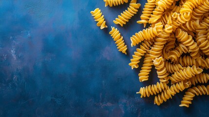 A vibrant overhead view of whole wheat pasta spirals against a blue backdrop, evoking freshness.