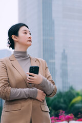 Confident Businesswoman Standing with Smartphone in Urban Environment