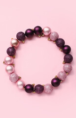 Frame made of Christmas tree balls on pink background