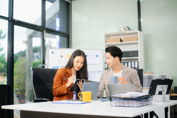￼￼Two young Asian professionals engaged in teamwork and business discussions in modern office