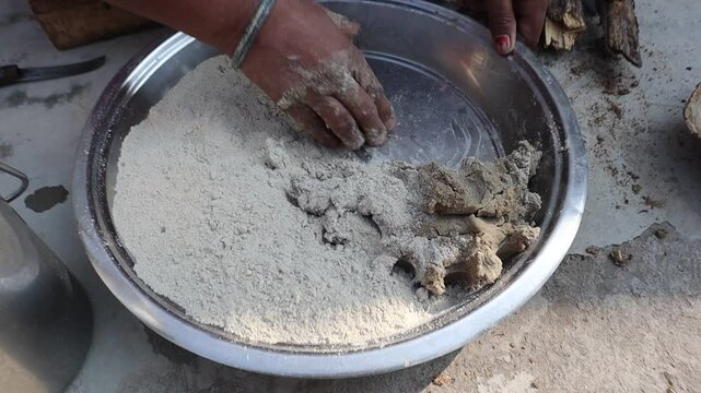 Indian woman cooking bajre ki roti on a traditional clay chulha, showcasing rural lifestyle and traditional cooking methods.
