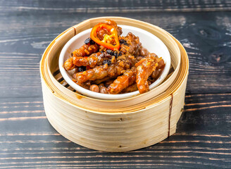 Braised Chicken Feet with Black Bean Sauce served in bamboo steamer isolated on wooden table side view of hong kong food