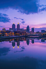 Naklejka premium Urban skyline at dusk with city lights reflecting on the river