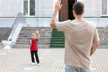 Father waving hand to his little son near school