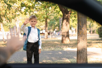 Father waving hand to his son near school, view from inside the car