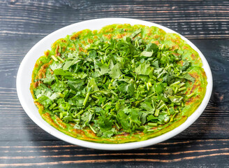 Savory Spinach Pancake topped with coriander served in dish plate isolated on wooden table side view of hong kong food