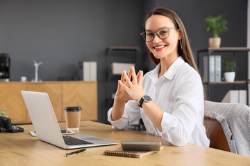 Young businesswoman with laptop on table in office