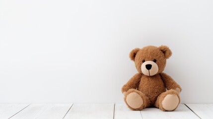 Obraz premium Teddy bear sitting on a wooden floor against a white background creating a cozy and nostalgic atmosphere for children's themes.