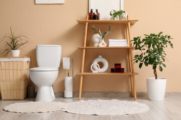 Interior of restroom with toilet bowl, shelf unit and laundry basket