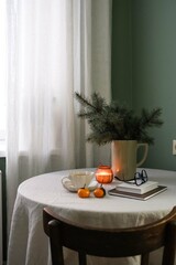 A beautifully warm indoor setting that includes delicious green tea, soft candles, and lovely seasonal greenery. Christmas mood.