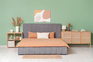 Interior of stylish bedroom with bed, wooden chest of drawers and bedside table