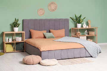 Interior of stylish bedroom with bed, chest of drawers and houseplants