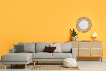 Cozy sofa, chest of drawers and mirror on yellow wall in living room