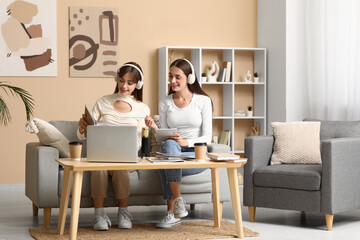 Young sisters in headphones with magazine recording podcast at home