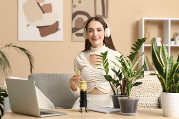 Young woman in headphones with plants recording podcast at home