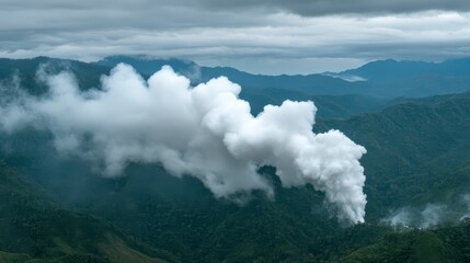 Obraz premium A landscape featuring billowing white smoke rising from a mountainous area, surrounded by lush green terrain and cloudy skies.
