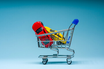 Toy cars inside mini shopping cart on blue background