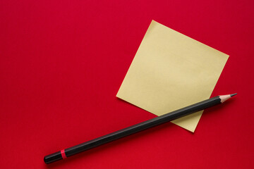 Yellow blank sticky note paper or post-it and pencil on red background