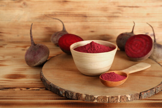 Bowl and spoon with beet powder on wooden background