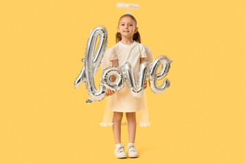 Cute little girl dressed as Cupid with air balloons in shape of word LOVE on yellow background....