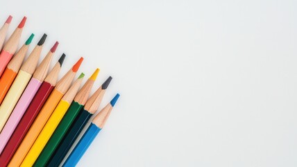 Fototapeta premium A colorful array of sharpened pencils lined up against a light background, ready for creative expression and artistic projects.