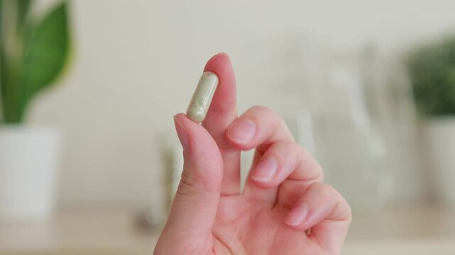Close-up Woman holding a gray capsule tablet with her fingers