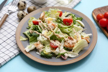 Plate with tasty chicken Caesar salad on blue background
