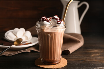Glass of sweet chocolate milk with marshmallows on wooden background