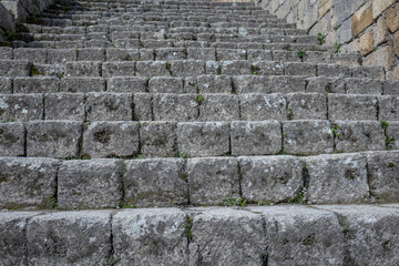 An ancient staircase made of large gray stone blocks. The background is made of stone blocks. The...