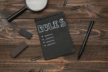 Notebook with blank list of rules and stationery on wooden background