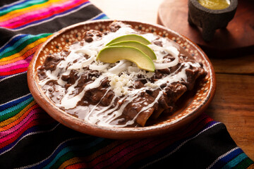 Enfrijoladas. Corn tortillas dipped in bean sauce, covered with cream and cheese, they can be covered or filled with chicken meat, cheese or some other ingredient. Traditional Mexican dish.