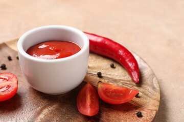 Wooden plate with bowl of fresh tomato paste, peppercorns and chili pepper on color background, closeup