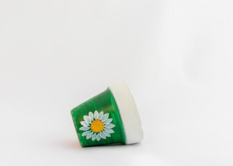 Hand painted daisy flower on a small clay pot laying on a white isolated background
