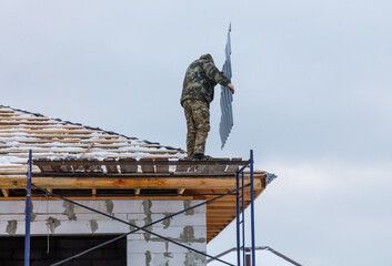 A man in a camouflage jacket is working on a roof