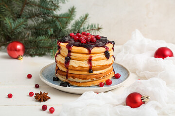 Plate of sweet pancakes with jam, Christmas balls and fir branches on white wooden table