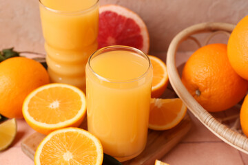 Wooden board with glasses of tasty juice and oranges on beige tile table