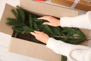 Woman putting Christmas tree in cardboard box at home, closeup