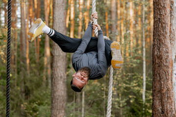 Stylish bearded man athlete doing training with rope holding it with hands, upside down. Training...