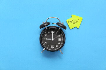 Alarm clock and sticky note with text RIGHT NOW on color background