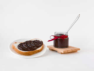 Delicious chocolate spread on bread with jar tied with red ribbon