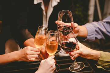 A group of friends enjoy an outdoor evening, drinking wine in a friendly and lively atmosphere. They celebrate togetherness, happiness and bonding.