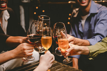 A group of friends enjoy an outdoor evening, drinking wine in a friendly and lively atmosphere. They celebrate togetherness, happiness and bonding.