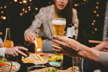 A lively group of friends celebrating with beer at an outdoor terrace. Raising glasses in cheerful toasts, they enjoy drinks, food, and laughter, embracing friendship, fun, and the vibrant party atmos