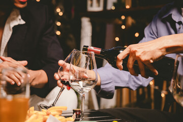 A cheerful group of friends enjoying wine and food on a sunny patio. Toasting with wineglasses, they celebrate togetherness in a scenic outdoor setting, blending fun, friendship, and a festive mood.