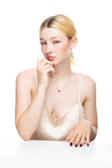 Naklejka premium A young blonde girl with freckles in a golden top. Beauty portrait of a woman on a white background in the studio.