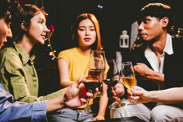 A joyful group of friends and family gathered around a dinner table, raising wine glasses in a celebratory toast. Smiling and laughing, they enjoy food, drinks, and togetherness in a festive atmospher