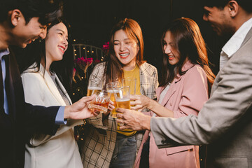 A group of cheerful friends celebrating, holding glasses of beer and laughing together. A lively gathering shows bonding, happiness and relaxation in a lively atmosphere.