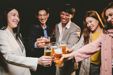 A group of cheerful friends celebrating, holding glasses of beer and laughing together. A lively gathering shows bonding, happiness and relaxation in a lively atmosphere.