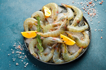 Raw shrimps with lemon slices and rosemary on table, side view. Seafood.